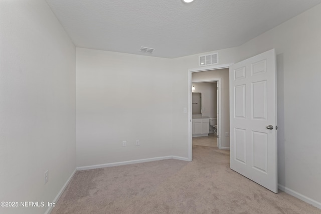 unfurnished room with visible vents, light carpet, a textured ceiling, and baseboards