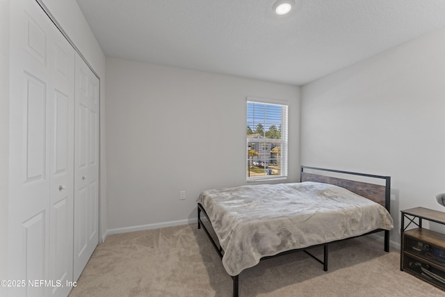 bedroom featuring light colored carpet, a closet, and baseboards