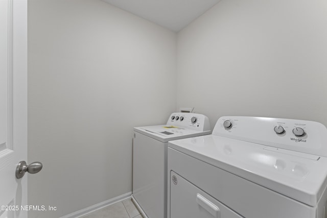 washroom featuring laundry area, light tile patterned floors, separate washer and dryer, and baseboards