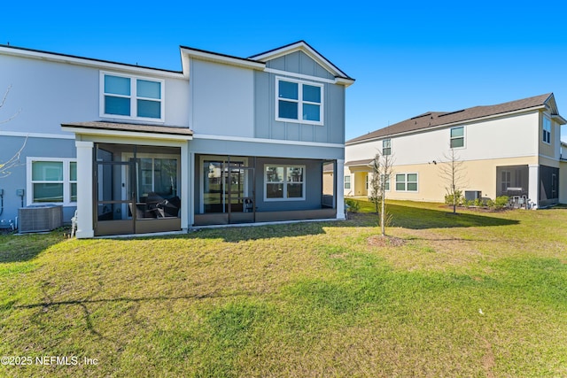 rear view of house featuring cooling unit, a sunroom, a yard, and board and batten siding