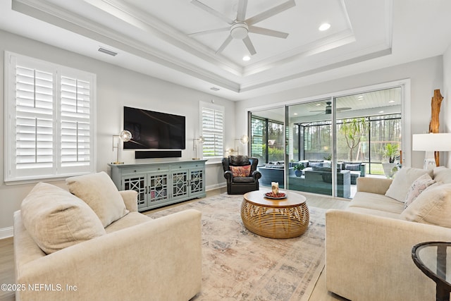 living room featuring visible vents, a tray ceiling, wood finished floors, a sunroom, and ceiling fan