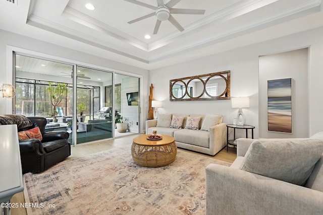 living area with a tray ceiling, wood finished floors, and a ceiling fan