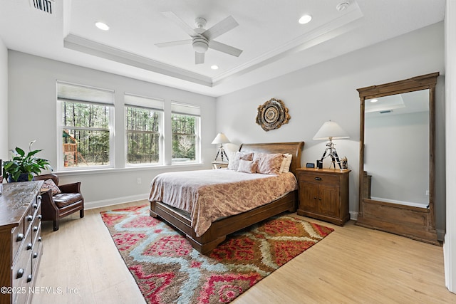 bedroom featuring a raised ceiling, visible vents, light wood-type flooring, and baseboards