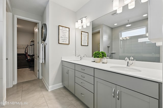 full bathroom with tile patterned flooring, double vanity, a tile shower, and a sink