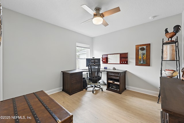 office space with a textured ceiling, baseboards, light wood-type flooring, and a ceiling fan