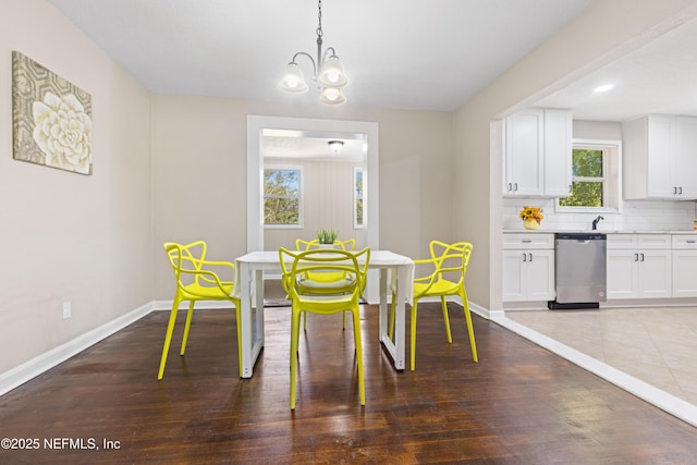 dining space with baseboards, a notable chandelier, and wood finished floors