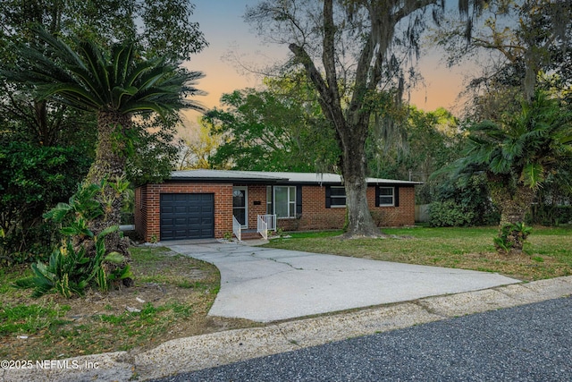 ranch-style house featuring a garage, a front lawn, brick siding, and driveway