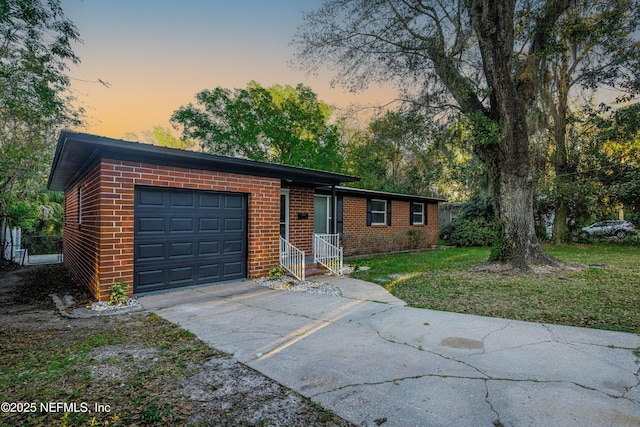 view of front of house with brick siding, concrete driveway, a garage, and a front yard