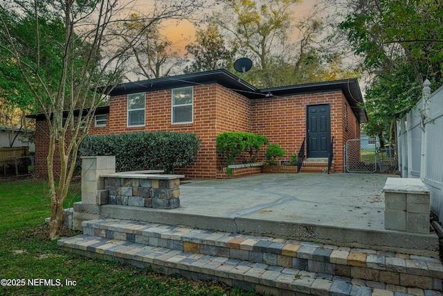 back of house featuring brick siding and fence