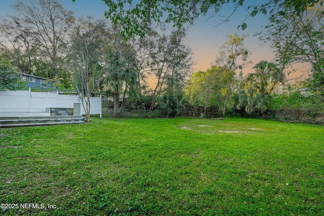 yard at dusk with a fenced backyard