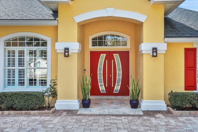 property entrance with french doors, roof with shingles, and stucco siding