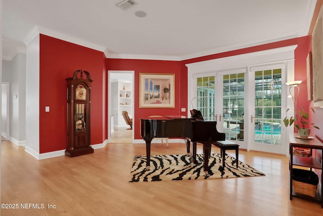 sitting room featuring visible vents, light wood-type flooring, and ornamental molding