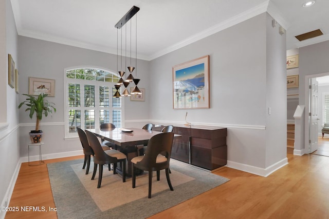 dining area with crown molding, a notable chandelier, baseboards, and light wood finished floors