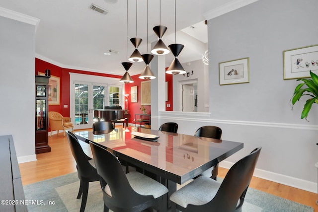 dining area with visible vents, light wood-style flooring, crown molding, and baseboards