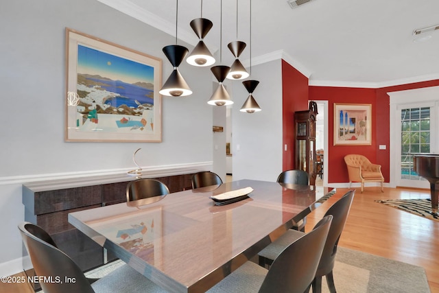 dining area with visible vents, wood finished floors, baseboards, and ornamental molding