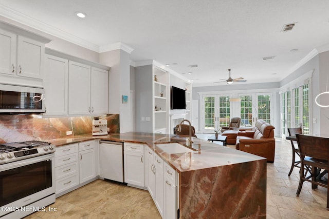 kitchen featuring visible vents, appliances with stainless steel finishes, a fireplace, a peninsula, and a sink