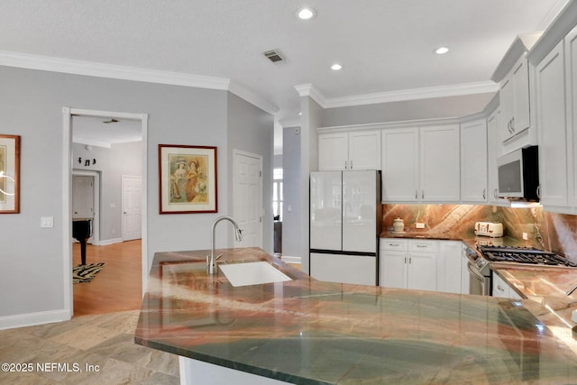 kitchen featuring visible vents, stainless steel gas stove, ornamental molding, a sink, and freestanding refrigerator