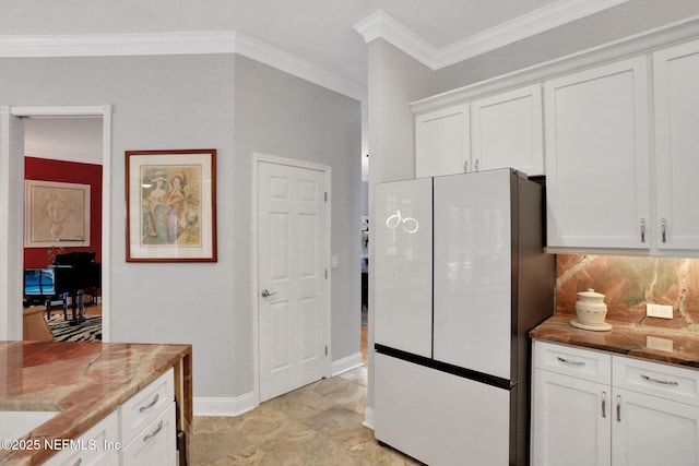 kitchen featuring decorative backsplash, white cabinetry, freestanding refrigerator, and ornamental molding