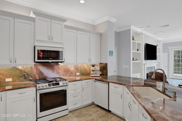 kitchen featuring white appliances, visible vents, a fireplace, a sink, and crown molding