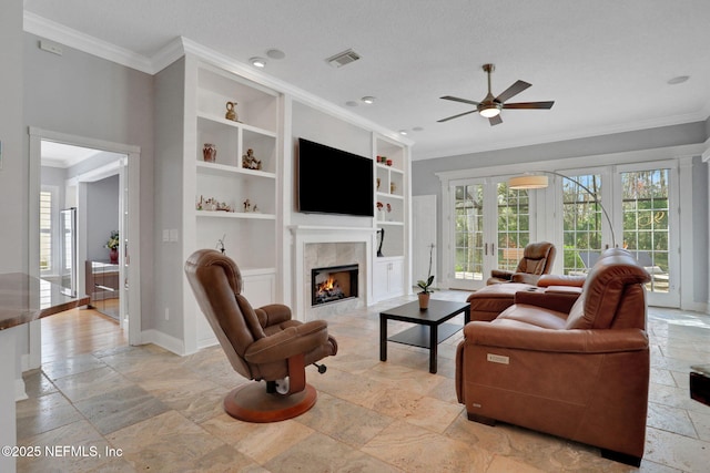 living area featuring visible vents, baseboards, built in features, ornamental molding, and stone tile floors