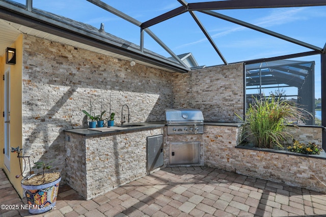 view of patio featuring a sink, glass enclosure, a grill, and exterior kitchen