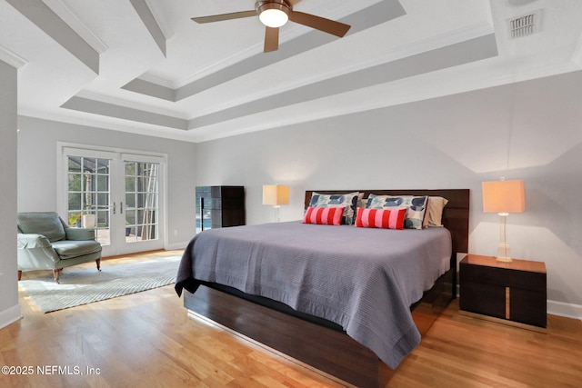 bedroom featuring french doors, a tray ceiling, and wood finished floors