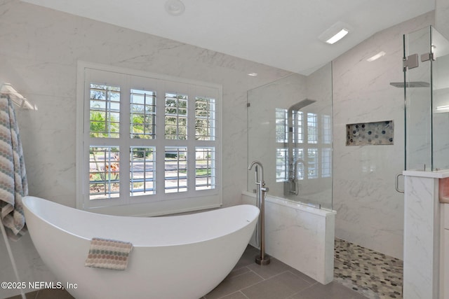 full bath featuring a marble finish shower, a freestanding bath, and tile walls