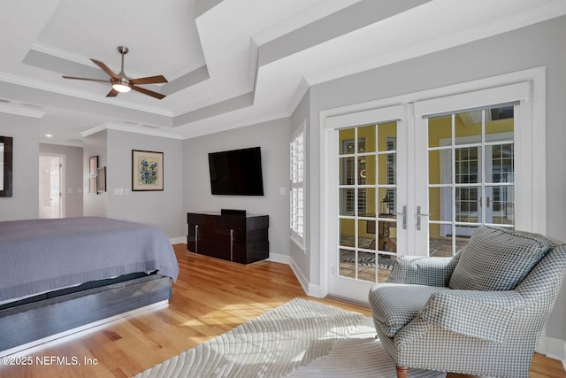 bedroom with a raised ceiling, wood finished floors, and crown molding