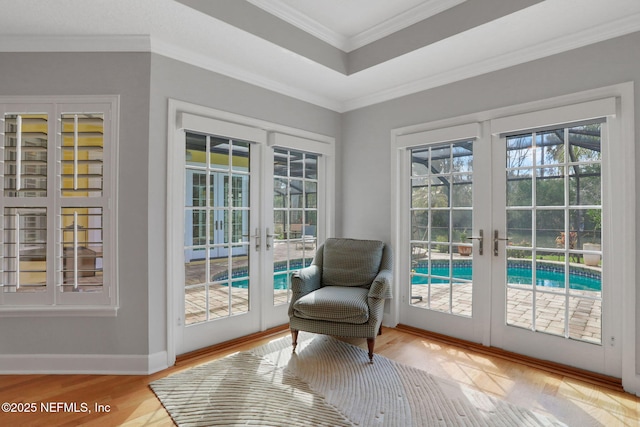 doorway featuring wood finished floors, baseboards, a tray ceiling, french doors, and crown molding