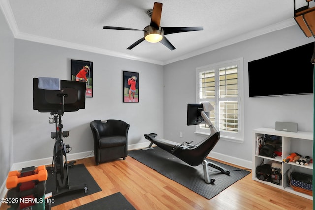 exercise room with baseboards, a ceiling fan, wood finished floors, and crown molding