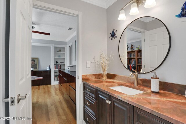 bathroom with visible vents, wood finished floors, ornamental molding, and vanity