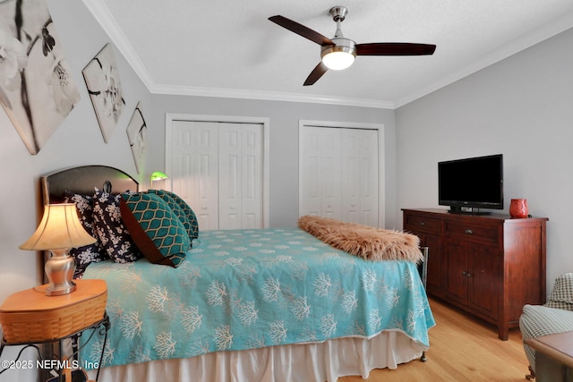 bedroom with multiple closets, light wood-style floors, ceiling fan, and crown molding