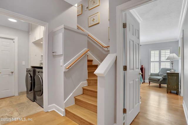 stairway featuring baseboards, separate washer and dryer, wood finished floors, and crown molding