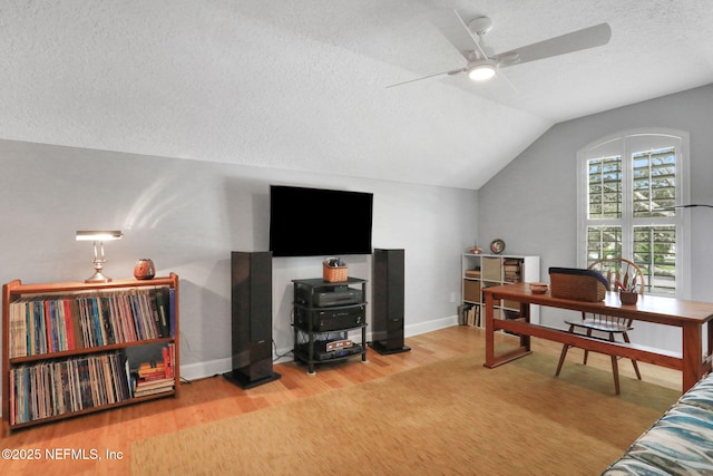 office area featuring baseboards, lofted ceiling, wood finished floors, a textured ceiling, and a ceiling fan