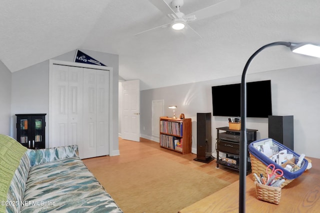 living area featuring a ceiling fan, a textured ceiling, wood finished floors, baseboards, and vaulted ceiling