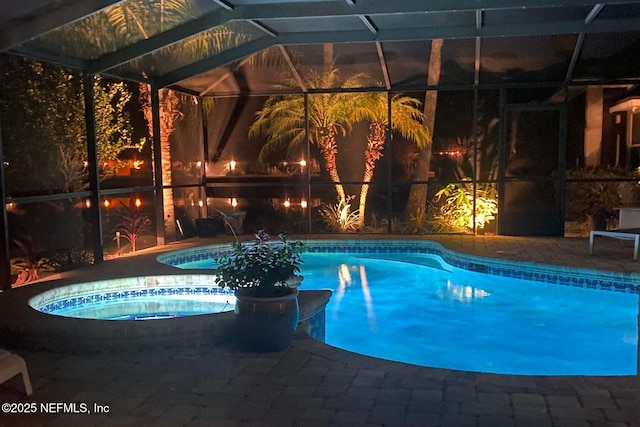 outdoor pool with glass enclosure, a patio, and an in ground hot tub