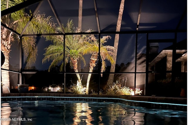 pool at night featuring a lanai