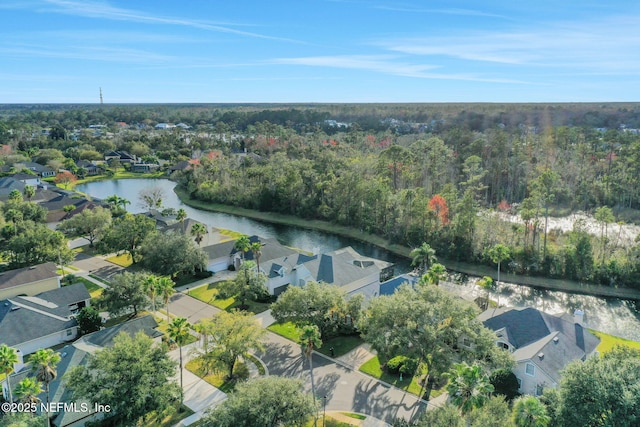 drone / aerial view featuring a residential view, a water view, and a view of trees