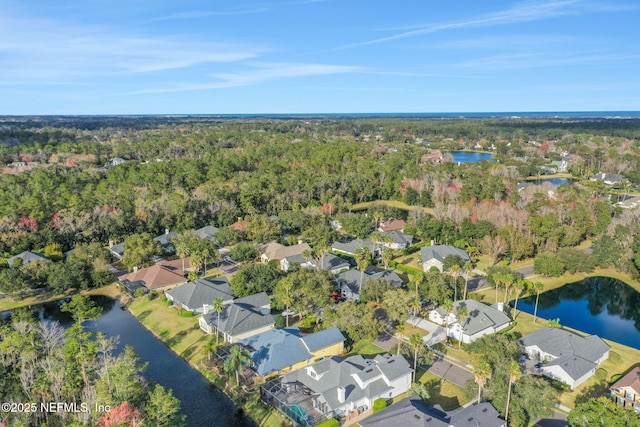 drone / aerial view with a wooded view, a water view, and a residential view