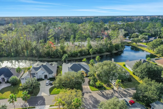 drone / aerial view with a forest view, a residential view, and a water view