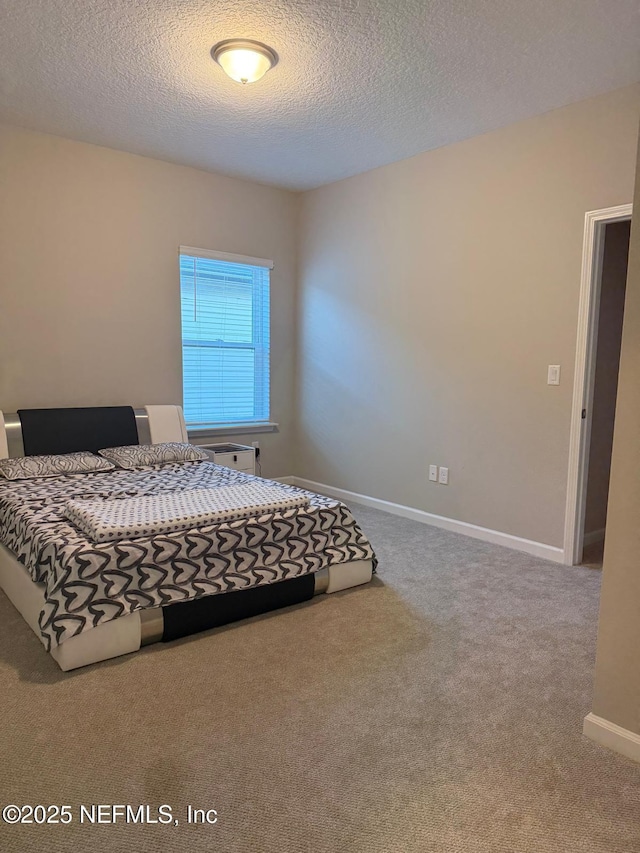 carpeted bedroom with a textured ceiling and baseboards