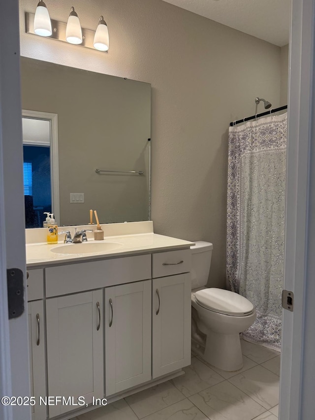 full bath with marble finish floor, toilet, vanity, and a shower with curtain