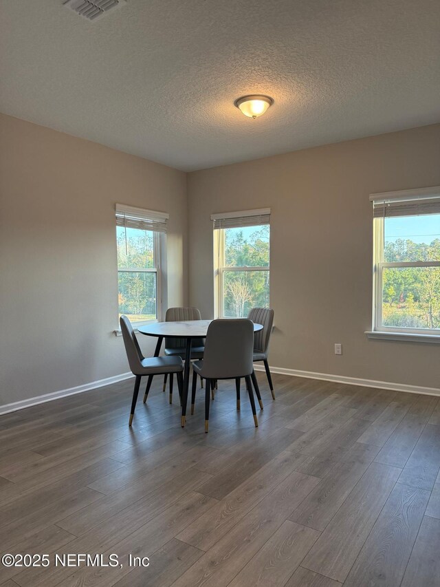 dining area featuring visible vents, baseboards, dark wood-type flooring, and a textured ceiling