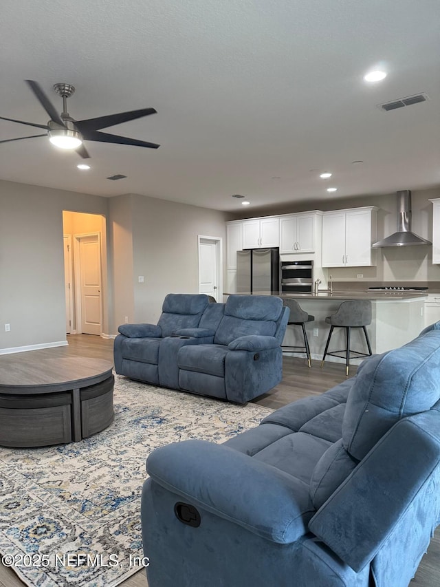 living area with recessed lighting, visible vents, baseboards, and wood finished floors