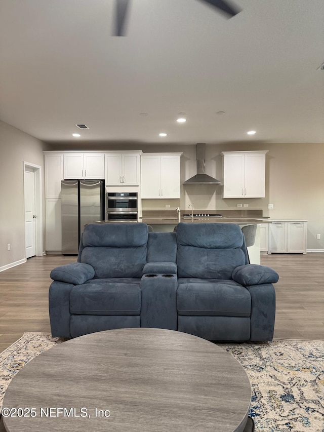 living room with light wood finished floors, visible vents, recessed lighting, and baseboards