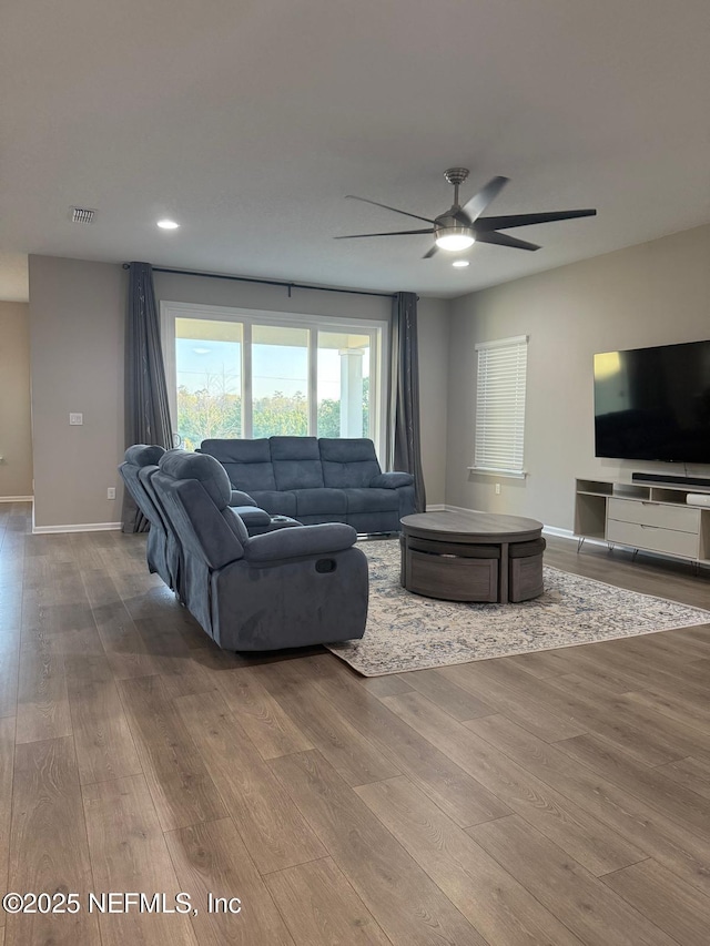 living room featuring visible vents, ceiling fan, baseboards, and wood finished floors