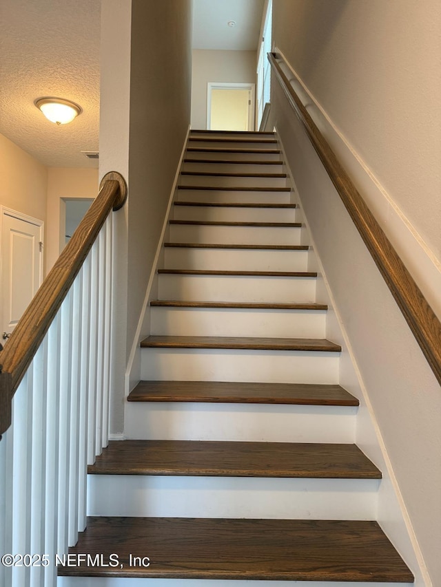 stairway with a textured ceiling