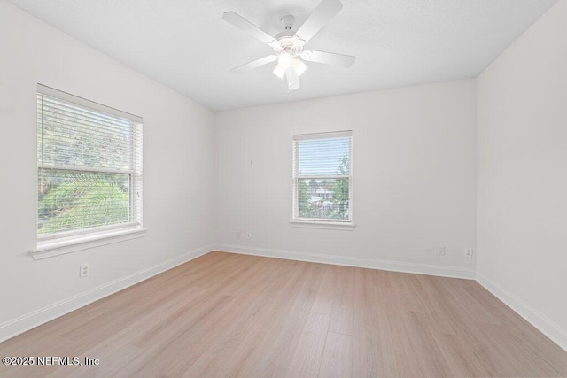 unfurnished room with plenty of natural light, baseboards, and light wood finished floors