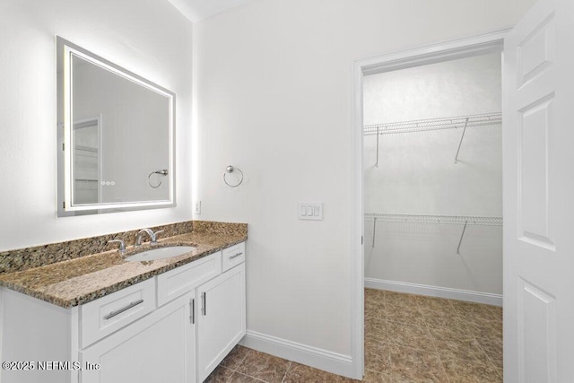 bathroom featuring vanity, a spacious closet, and baseboards