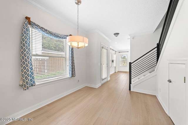 interior space featuring baseboards, light wood-type flooring, stairs, ornamental molding, and a textured ceiling